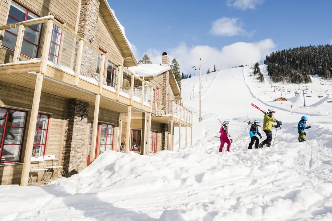 En familj går från stugan direkt ut i backen med skidorna.