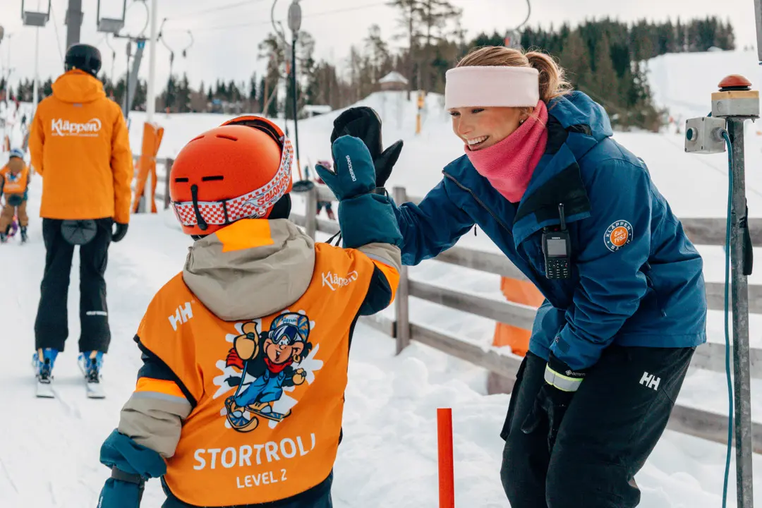 En liftvärd hejar på en skidskoleelev
