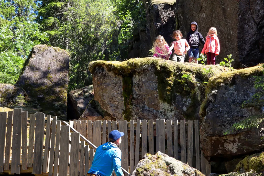 barn och en pappa är på upptäckstfärd i Trollsterhusen, Barnen står uppe på ett stort klippblock.  