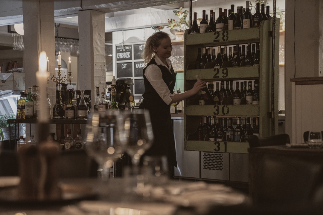 En servitris plockar bland vinflaskor