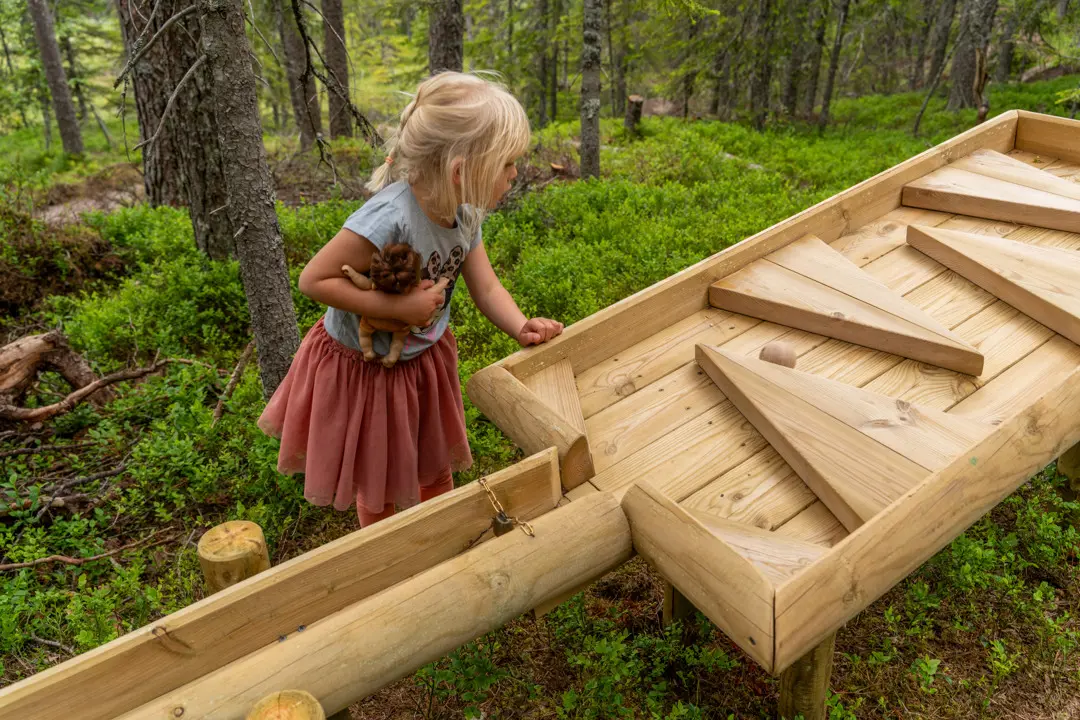 En lite flicka står vi kulbanan och ser på när kulan rullar iväg 