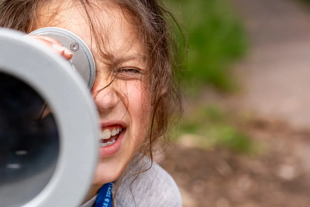 Ett barn som kikar i en kikare för att lösa en gåta på Trolle & Trollas Äventyr